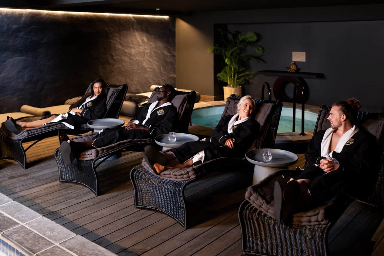 People laying on chairs near the pool at The Grotto Spa